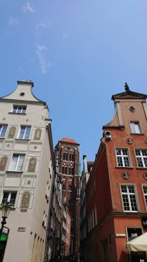 Gdansk, Polonya. Haziran 07, 2019. Uzaklardan görünen tuğla kulesi olan tarihi konutlar tarafından çerçevelenmiş dar bir eski kasaba caddesi boyunca manzara.