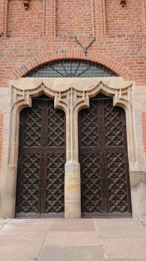 GDANSK, POLAND - 07 Haziran 2019: Tarihi St. Mary Kilisesi 'nin taş gotik kapısı olan dekoratif, ahşap bir giriş kapısı.