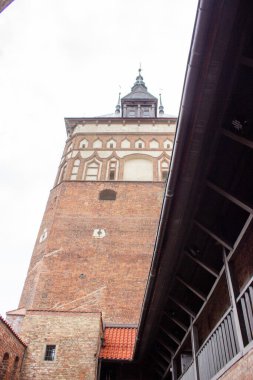 Gdansk, Polonya. Haziran 07, 2019. Tarihi ortaçağ tuğla kulesi, Eski Kent savunma mimarisinin bir parçası olan ahşap bir galerinin ve avlu binalarının üzerinde yükseliyor..