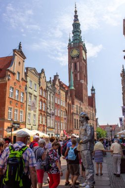 Gdansk, Polonya. Haziran 07, 2019. Canlı heykel gibi giyinmiş bir sokak sanatçısı, tarihi Long Market 'te turistler arasında duruyor. Arka planda da ana şehir kulesi var..