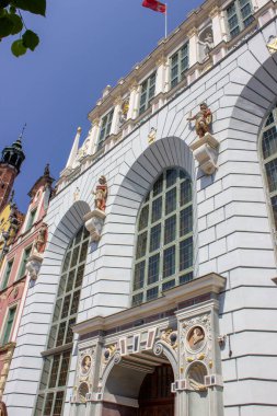 Gdansk, Polonya. Haziran 07, 2019. Güneşli bir yaz gününde eski kasabanın heykel figürleri ve kemerli camlarıyla tarihi bina cephesini süsleyin..
