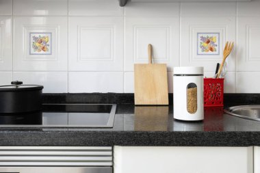 Modern mutfak iç mimarisi granit tezgah, indüksiyon sobası ve çeşitli ev yapımı yemek malzemeleri.