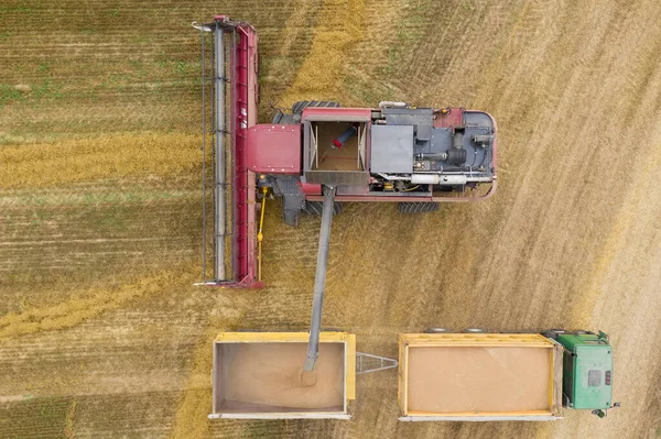 Top view of the process of loading grain from the combine to the tractor trailer