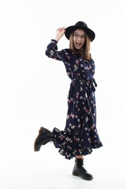 Kameraya poz veren uzun çiçekli elbiseli genç bir kadın. 