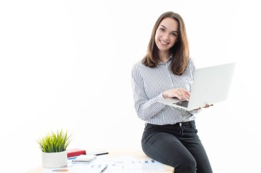Masada oturan ve bilgisayarda yazan genç bir kadın. 
