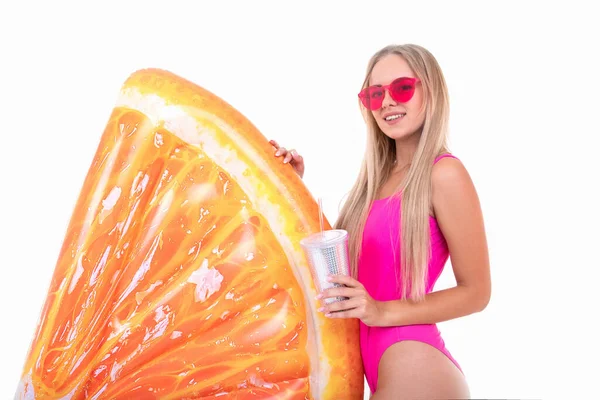 一位穿着粉色游泳衣的年轻女子喝柠檬水 还拿着一个气垫 — 图库照片