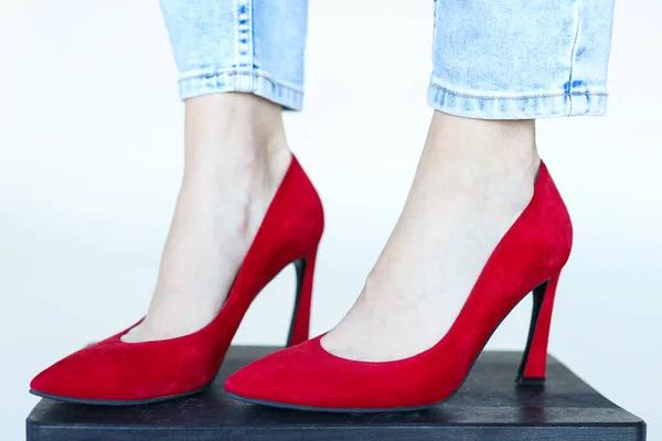 Feet in red heeled shoes on a white background