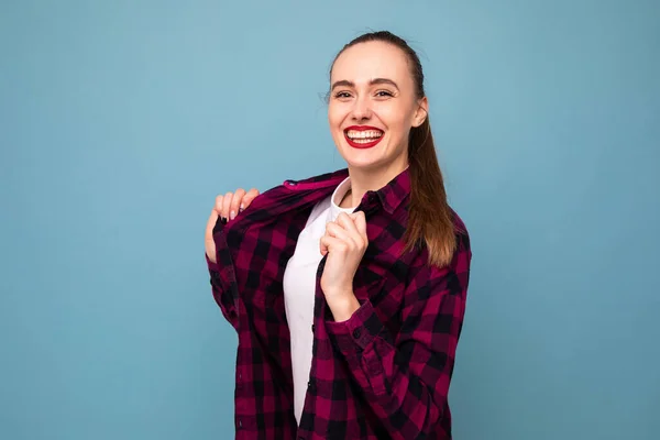 A young woman in a white t-shirt and a plaid shirt poses for the camera