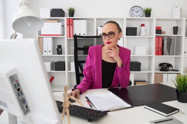 İş stili olan bir kız ofisindeki bilgisayarda çalışıyor.