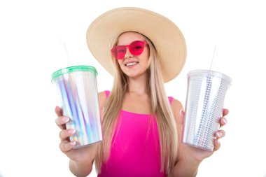 Pembe mayolu ve şapkalı genç bir kadın limonata için iki bardak tutuyor.