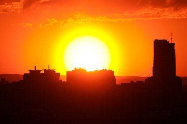 Şehrin binalarının üzerinde parlak kırmızı gün batımı