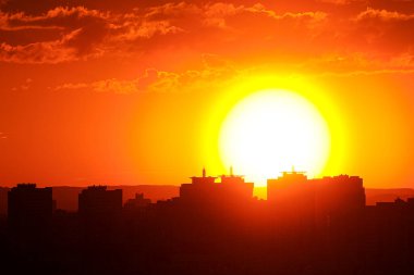 Şehrin binalarının üzerinde parlak kırmızı gün batımı