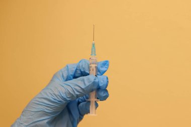 Bir hemşirenin elinde aşı olan bir şırınganın yakın çekimi.