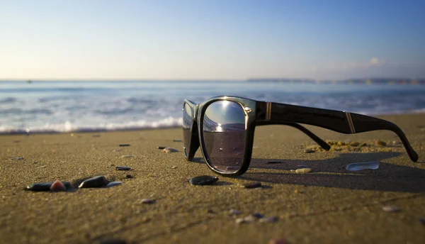Solglasögon på stranden vid havet — Stockfoto