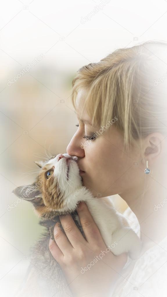 A young blonde girl kisses  kitty