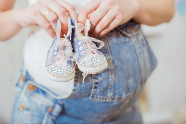 Belly of a pregnant woman in a blue denim overalls. Hands folded on pregnant woman belly — Stock Photo, Image