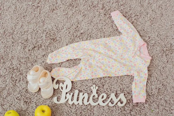 Ropa y calzado para bebés y manzanas. Princesa de la placa de decoración del hogar — Foto de Stock