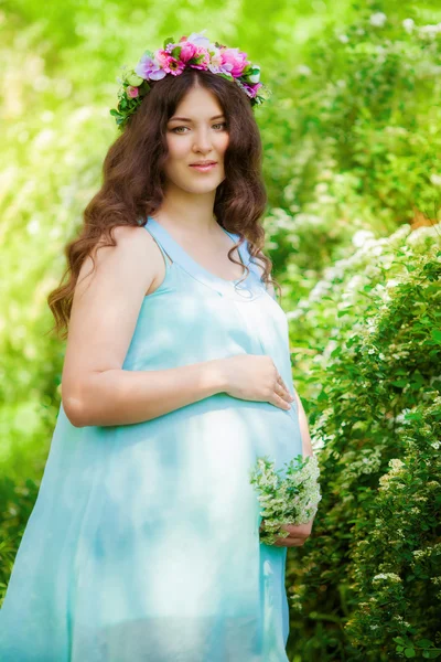 春の花の咲く庭で若い妊婦 — ストック写真
