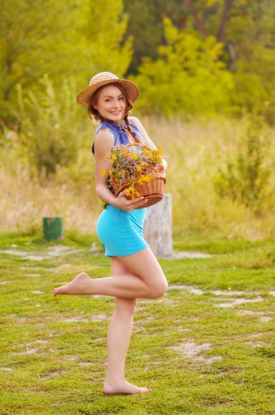 Mooi jong meisje met een rieten mand met bloemen — Stockfoto
