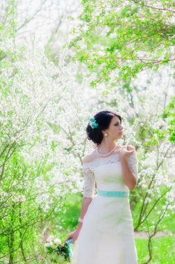 Bahar Çiçek bahçesinde genç güzel gelin. Bir düğün buket bahar bahçe Beyaz giysili bir gelinle