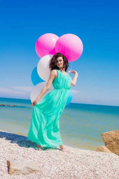 Menina bonita na praia no verão com balões coloridos — Fotografia de Stock