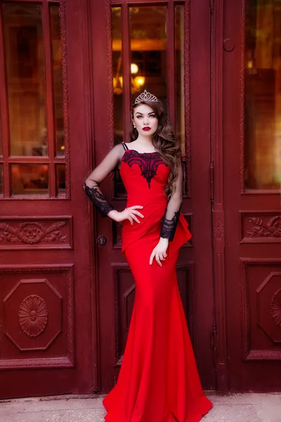 The beauty queen in a red dress with long hair and a tiara on her head — Stock Photo, Image