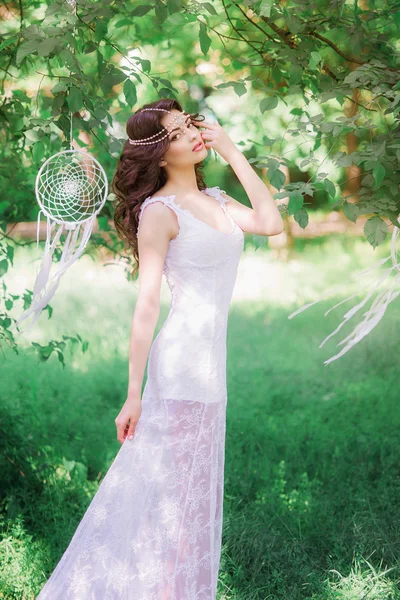 Hermosa chica con el pelo largo rizado en un vestido blanco en un parque de verano. Chica con el atrapasueños —  Fotos de Stock