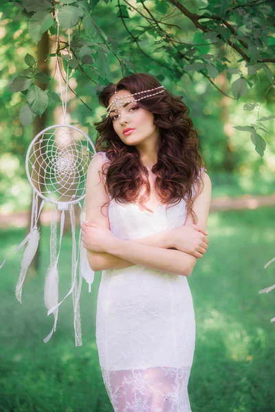 Hermosa chica con el pelo largo rizado en un vestido blanco en un parque de verano. Chica con el atrapasueños — Foto de Stock