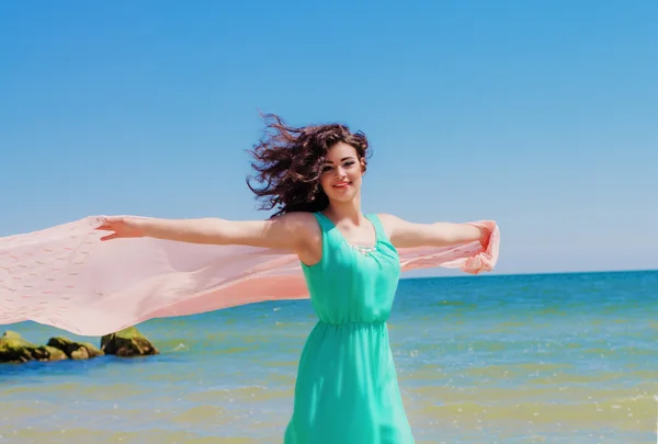 Young girl on the beach in summer in a beautiful dress with a flying scarf — Stock Photo, Image