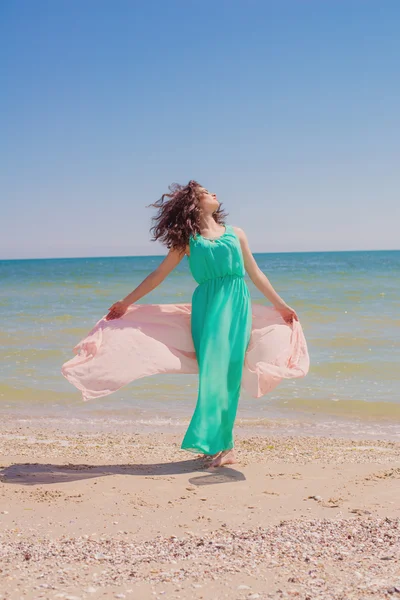 Young girl on the beach in summer in a beautiful dress with a flying scarf — Stock Photo, Image