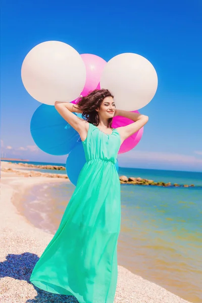 Девушка на пляже с цветными воздушными шарами — стоковое фото