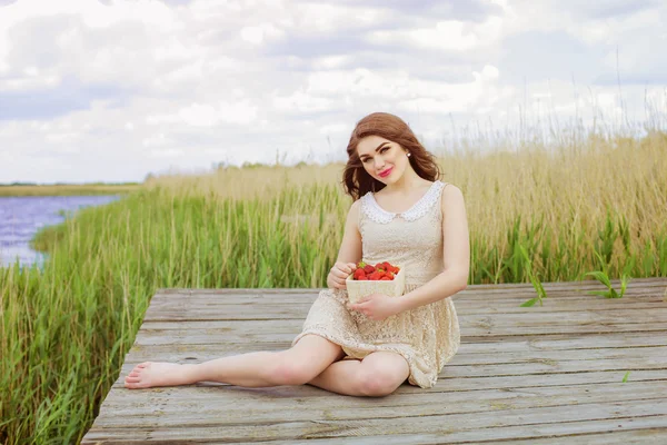 Meisje met lang haar in water in de zomer met aardbeien — Stockfoto