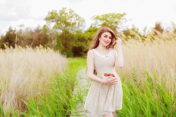 Ragazza con i capelli lunghi in acqua in estate con fragole — Foto Stock