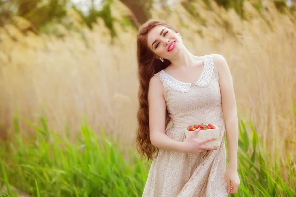 Ragazza con i capelli lunghi in estate con fragole — Foto Stock