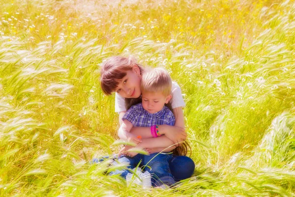 Petit garçon et fille dans le champ d'été avec des fleurs — Photo