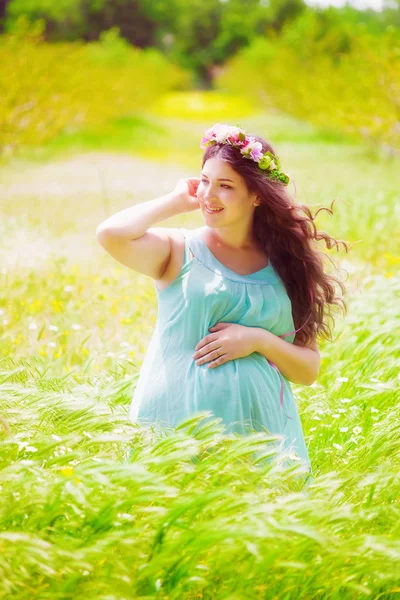 Беременная женщина с длинными вьющимися волосами летом — стоковое фото
