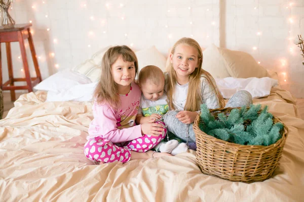 크리스마스 복장을 침대에 바늘을 스칸디나비아식 침실에서 잠옷을 귀여운 자매와 남동생이 — 스톡 사진