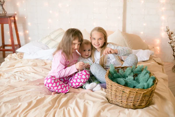크리스마스 복장을 침대에 바늘을 스칸디나비아식 침실에서 잠옷을 귀여운 자매와 남동생이 — 스톡 사진
