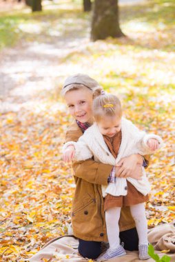 Ağabeyi ve küçük kız kardeşi sonbahar parkında yürüyor ve gülüyorlar. Aile ve çocuklar. Sonbahar havası