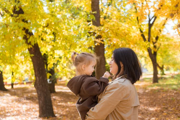 幼い母親と小さな娘が秋の公園を歩いて笑っています 家族だ 秋の気分 — ストック写真