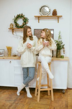 Kızlar mutfakta sıcak kakao dolu süveter örüyorlar.