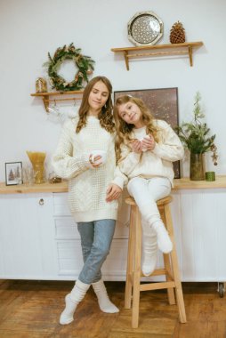 Kızlar mutfakta sıcak kakao dolu süveter örüyorlar.