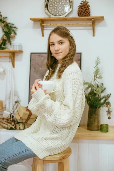 在厨房里穿着温暖轻薄针织毛衣的女孩 手里拿着一杯温暖的可可 — 图库照片