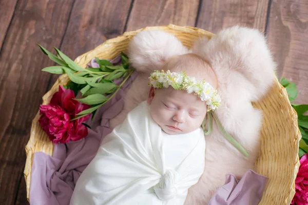 薄い巻きでバーガンディ牡丹で飾られたつるのウィッカーバスケットの赤ちゃんの女の子と彼女の頭の上に花の花輪 春の写真 花や子供たち 幸せな母親 — ストック写真