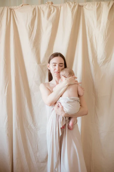 一位年轻的母亲 深色长发 赤身裸体 怀里抱着一个孩子 背景浅薄 健康的生活方式母性快乐 — 图库照片