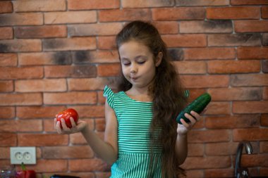 Okul çağındaki tatlı küçük kız mutfakta taze organik sebzelerle. Sağlıklı bebek maması. Sağlıklı yaşam tarzı 