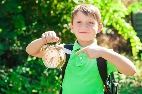 Junge mit Rucksack und Uhr in der Hand — Stockfoto