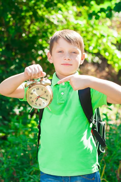 Chłopiec z plecaka i zegar w ręce — Zdjęcie stockowe