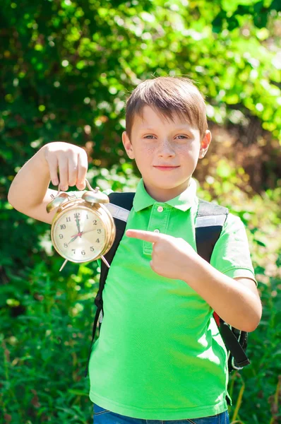 Niño con una mochila y un reloj en las manos —  Fotos de Stock