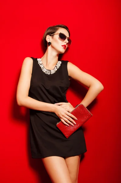 güzel bir kız ile bir clutch çanta ve güneş gözlüğü